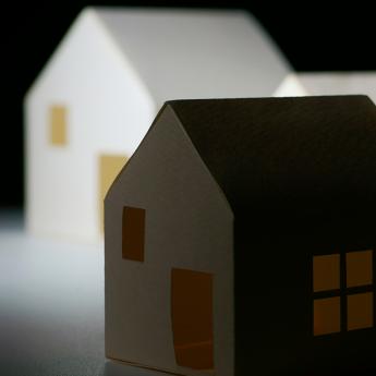 A model of a small house sits in the shadows of much larger houses