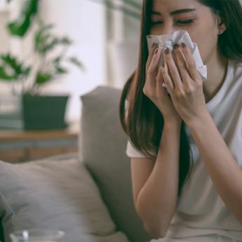 A woman with Covid-19 symptoms uses a tissue