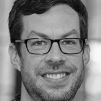 Professor Austin Carson smiles wearing glasses