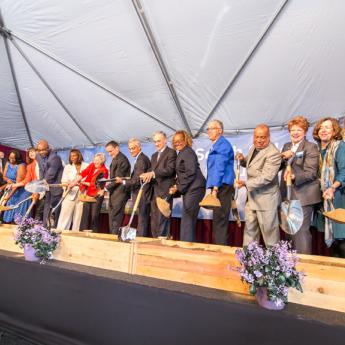 People on stage holding shovels