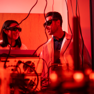 Researchers operate large scientific equipment while wearing protective glasses